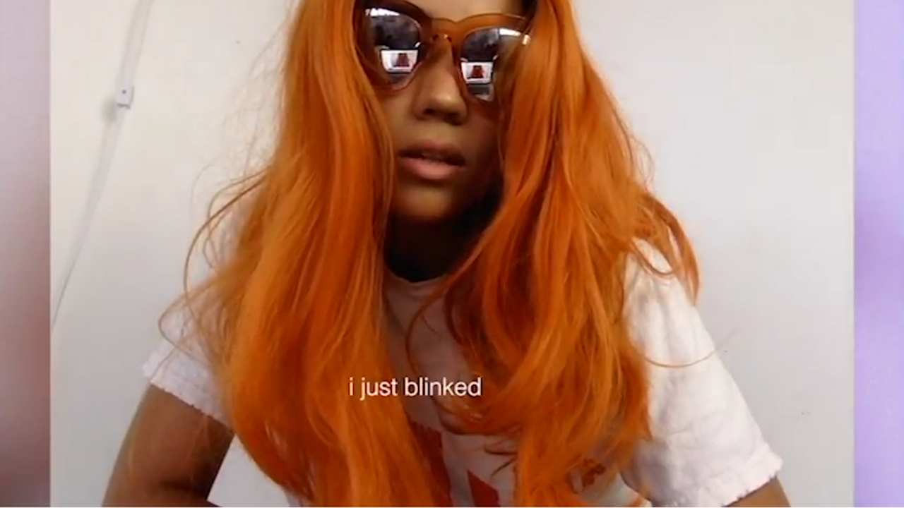 a girl with bright orange hair and mirrored shades